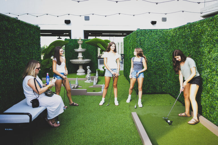 Drive Shack's Puttery mini golf transforms putting into an artistic journey amidst a vibrant outdoor garden.